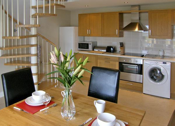 A kitchen diner with oven, washing machine, toaster and table for two.