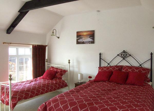 Oak-beamed family bedroom with a double and single bed and bedside tables