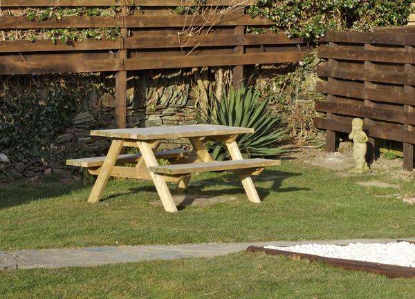 A picnic bench in a grassy corner of a garden.