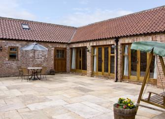 A courtyard barn conversion with a frontage comprising wall-to-ceiling French windows.