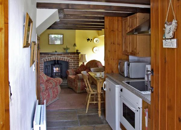 View through a kitchen with an oven, fridge and microwave.