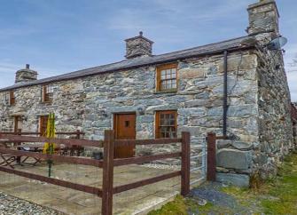 An end-terrace stone-built Gwynedd holiday cottage with a paved, secure front patio.