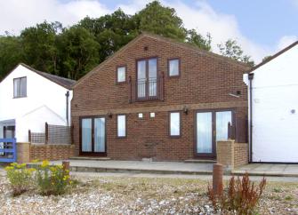 A modern cottage with floor-to-ceiling windows and a Juliet balcony.