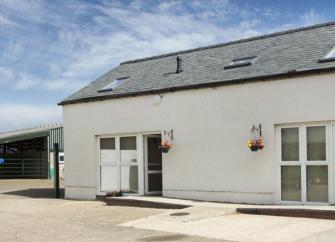 A slate-roofed barn conversion overlooks a farmyard.