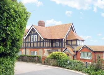 Exterior of a large Mock Gothic brick house bordered by a stone wall.