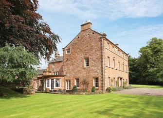 A Large 3-storey Country House surrounded by lawns and woodland.