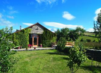 The Gable end of a single-storey barn conversion overlooks a country garden.