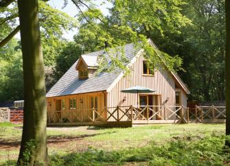 A 2-storey, timber-walled lodge in a woodland glade.