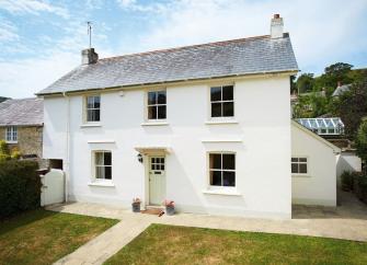A double fronted East Devon holiday cottage in front of a secure lawned garden.