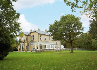A large countryt house  overlooks spacious grounds scattered with mature oak trees.