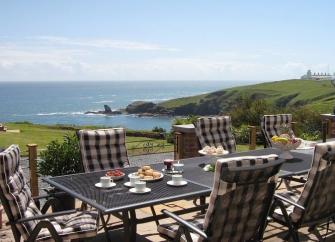 Chairs around an outdoor dining table offer beautiful sea views.