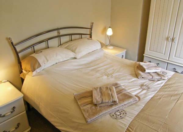 Doubkle bedroom with twin beside cabinets, table lamps and a wardrobe.