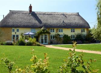 A large thatched cottage overlooking a spacious lawn near Bridport.
