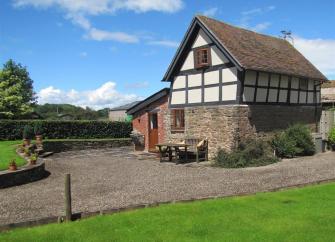 A historic black-and-white-timbered Herefordshire barn conversion with a large lawn.