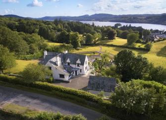 Aerial view of a holiday cottage surrounded by fields overlooking Lake Windermere.