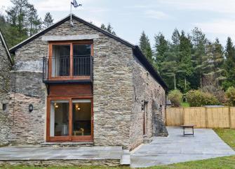 Two-storey barn conversion with large terraces and a fenced lawn.