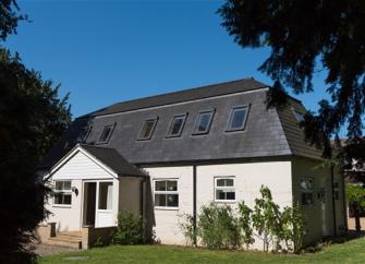 Exterior of a 2-storey coach house conversion with covered porch and garden lawn