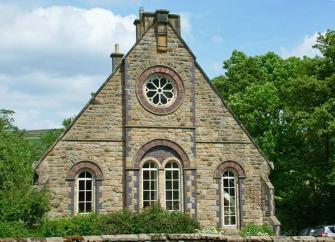 A chapel conversion with a large rose window sits behind a low stone wall.