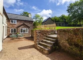 A stone-built cottage overlooks a large lawn and courtyard.