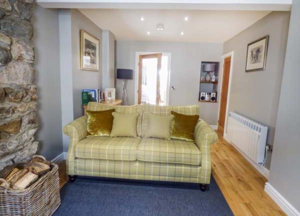A Llyn Peninisula cottage lounge with a sofa, TV and woodburner.