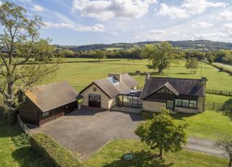 Aerial view of a contemporary farm house surrounded by open fields.