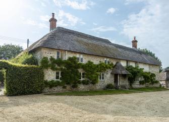 Large, thatched Dorset Farmhouse overlooking a courtyard.