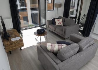 A holiday apartment lounge with sofas and French windows leading to a balcony