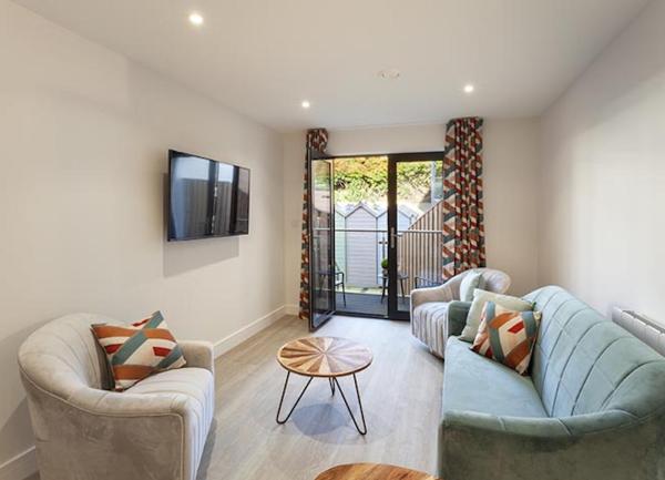 Lounge area with sofa, armchair, wall-mounted TV and French windows to a Juliet balcony.