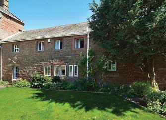 A long, 2-storey farm cottage overlooking a spacious lawn.