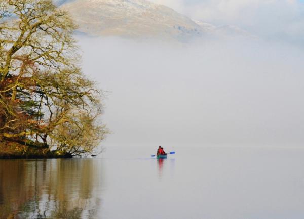 Winter canoeists in the mist of a calm lake