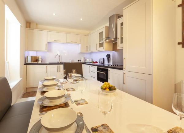 Kitchen diner with fitted units, worktop appliances and a long dining table laid for breakfast.