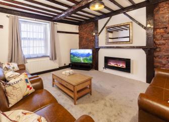 An oak beamed lounge with woodburner, wide-screen TV and a sofa.comfy