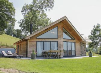 Gable end of a contemporary wooden lodge in Powys with floor-to-ceiling windows