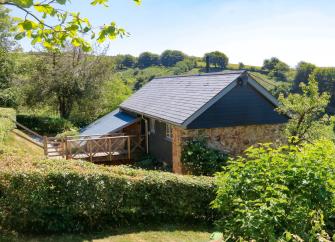 A single storey barn conversion in North Devon surrounded by gardens and tall hedge rows.