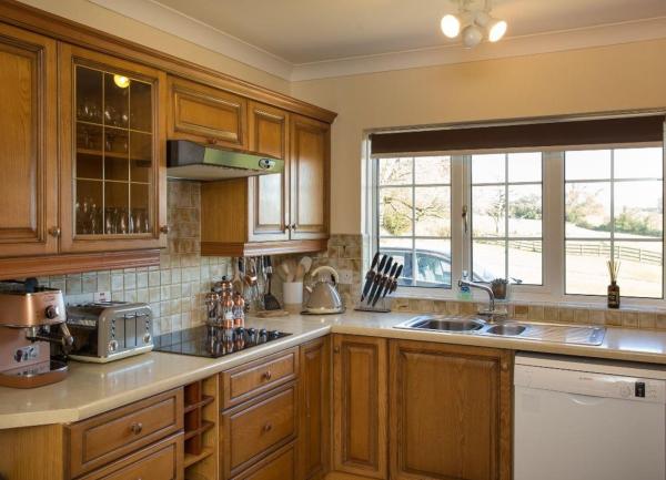 Kitchen corner with fitted wall and floor units containing an infra-red oven top, dishwasher and many storage cupboards.