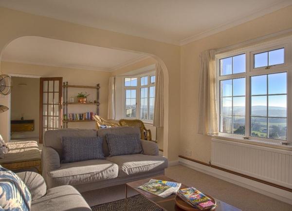 A lounge with sofas, armchair, coffee table and far reaching rural views through ther windows.
