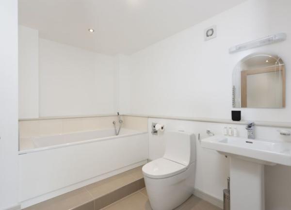 Bathrooom with bath with a shower screen.