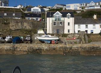 A waterfront terrace overlooks a harbour with small boats stored on the Quay.