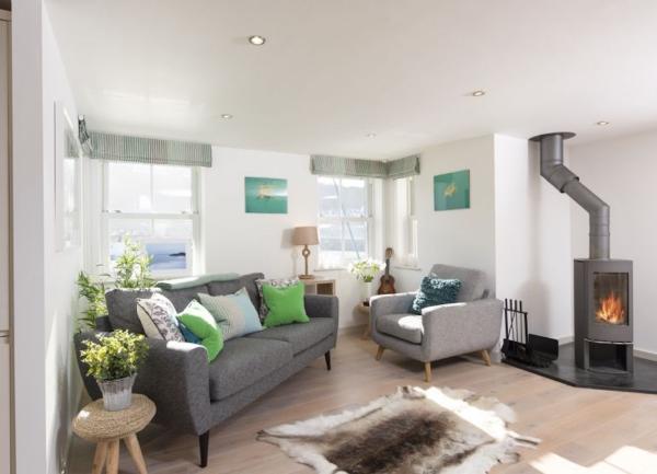 Lounge with sofa, armchair and woodburner.