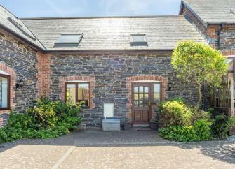A semi-detached Cornish cottage overlooks a block-paved courtyard.