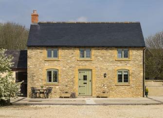 Exterior of a double-fronted Cotwolds honey-stone cottage