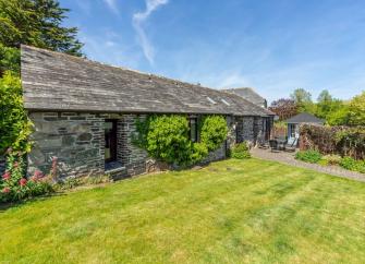 A single-storey stone barn conversion in Polzeath sits alongside a large lawn.