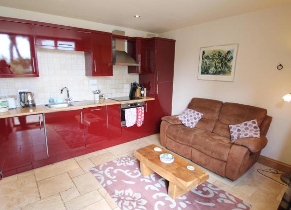 A  fitted kitchenette in a cottage for couples has a comfortable leather sofa.