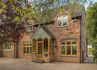 A brick-built 1930s cottage with covered porch and block-paved courtyard.