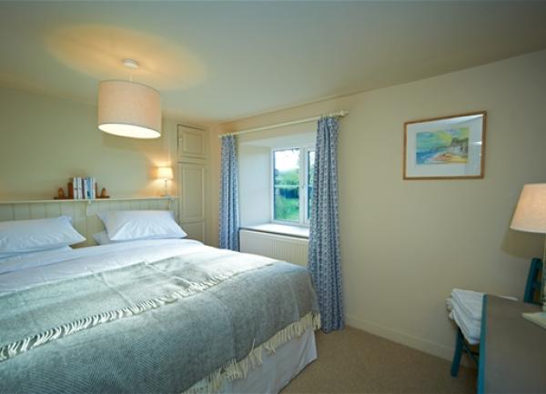 Double bedroom with king-sized bed, chair and dressing table.