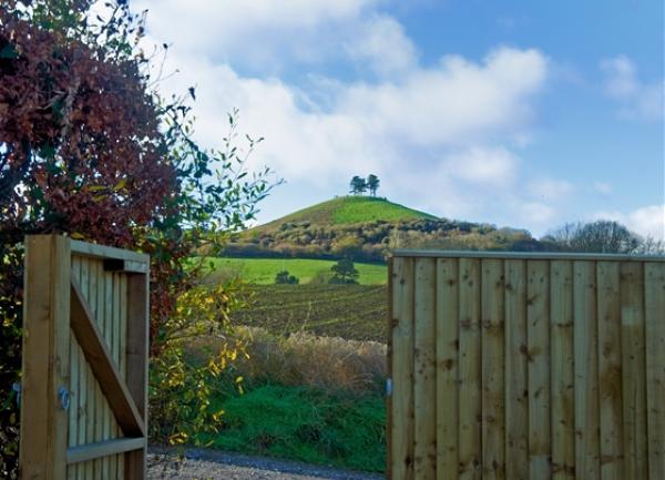 An open wooden gate reveals far reaching rural views.