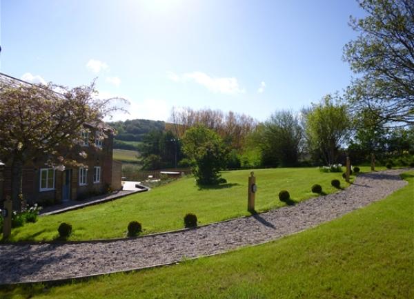 A farmhouse overlooks a sloping garden and shingled path.
