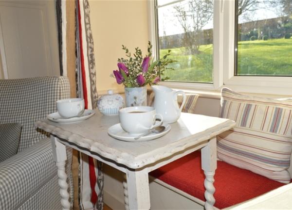Lounge with a side table laid for tea overlooking a lawned garden.