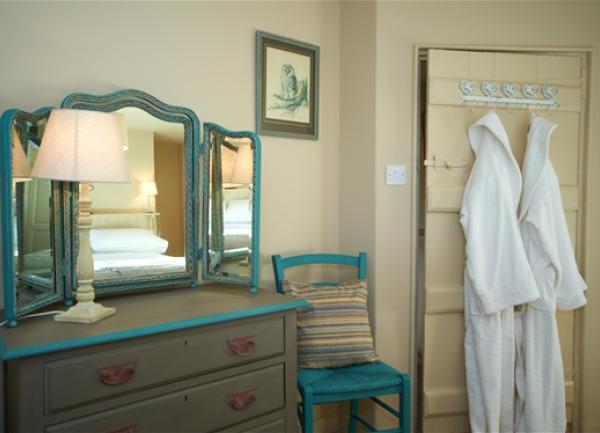 White towel dressing gowns for guests hand on a bedroom door.