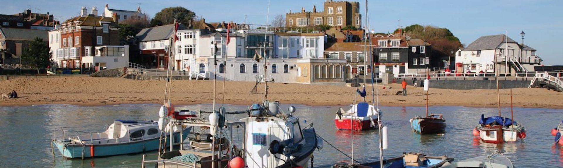Fishing boats in Broadstairs moored off a shingle beach behind which stand a huddle of old fishermen's cottages